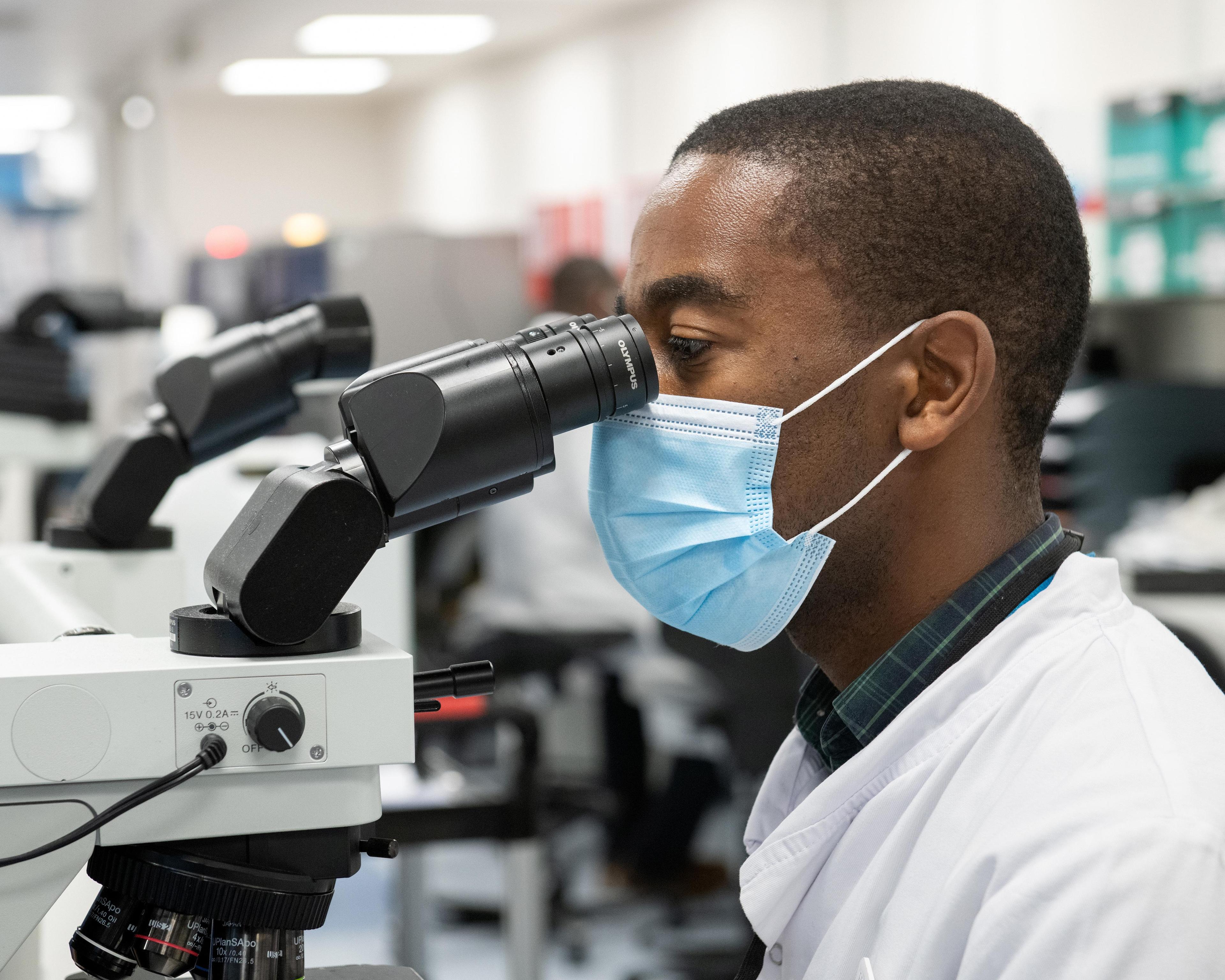 Technician looking into microscope