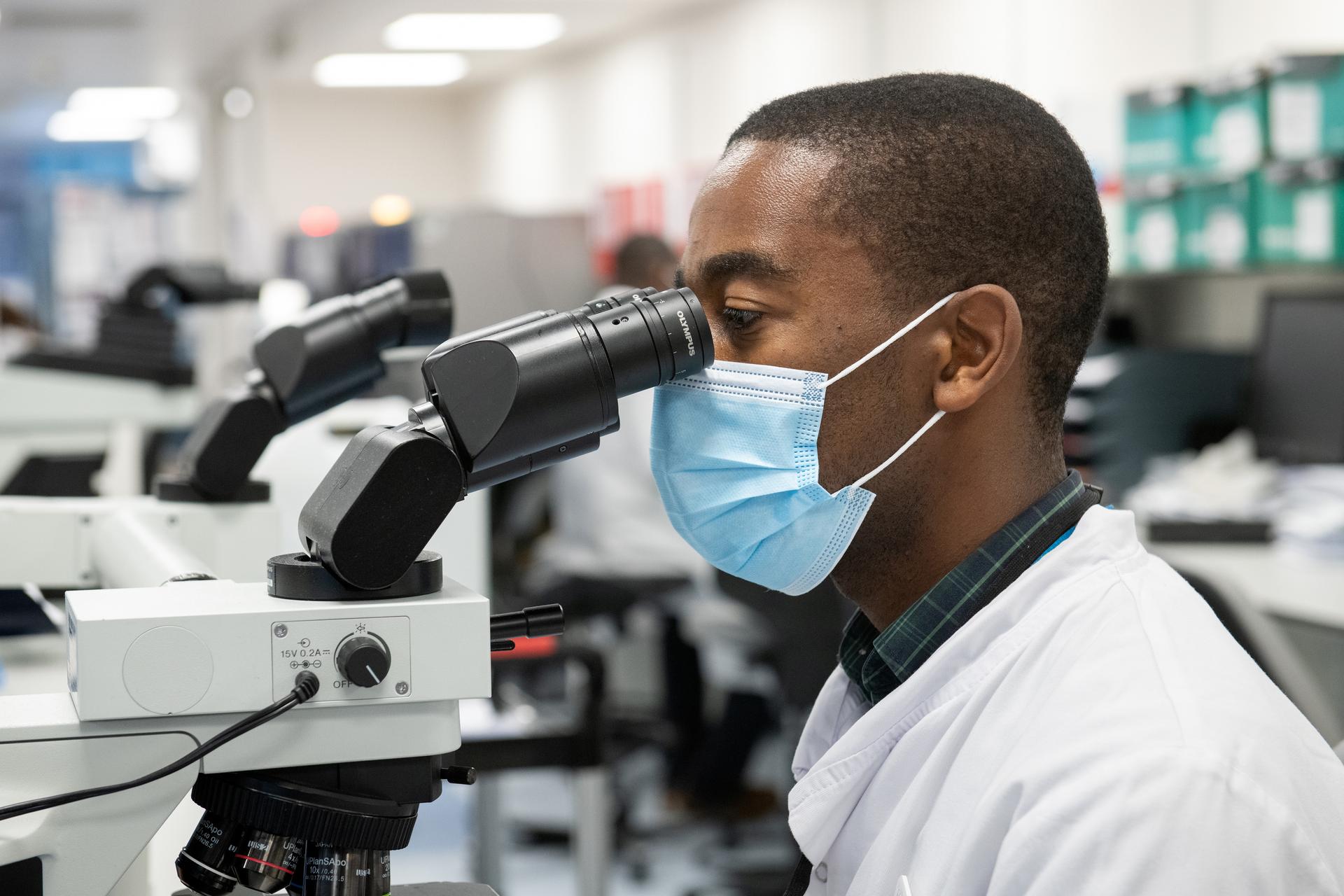 Technician looking into microscope